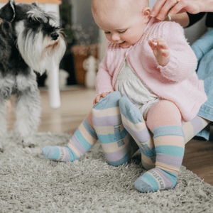 Baby wearing Lamington merino knee high socks with pastel blue, yellow, green and lilac stripes made in New Zealand.