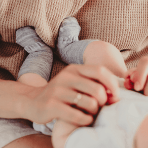Baby wearing Merino Wool Crew Socks in light grey while a parent holds them.