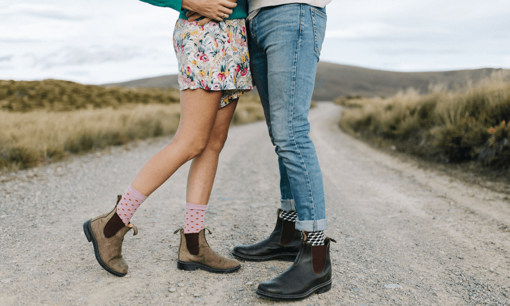 Couple in fashionable boots on a dirt road, showcasing the 2024 fashion collection release.